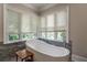Bright bathroom with a free-standing tub centered under dual windows with white blinds at 8470 Lazy Oaks Ct, Atlanta, GA 30350