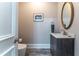 Powder room with oval gold mirror, gray vanity, and a marble countertop at 8470 Lazy Oaks Ct, Atlanta, GA 30350