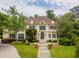 Elegant two-story home with a well-manicured lawn, lush greenery, and a charming stone walkway leading to the front entrance at 8470 Lazy Oaks Ct, Atlanta, GA 30350