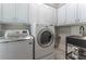 Well-equipped laundry room with a washer, dryer, utility sink, and storage cabinets at 8470 Lazy Oaks Ct, Atlanta, GA 30350