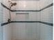 Close-up view of glass shower with subway tile surround, blue glass accents, and rainfall shower head at 8470 Lazy Oaks Ct, Atlanta, GA 30350