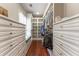 Walk-in closet with white custom shelving and drawers, hardwood floors, and a bench seat at 8470 Lazy Oaks Ct, Atlanta, GA 30350