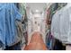 Large walk-in closet with custom shelving and drawers with clothes hanging from the rods at 8470 Lazy Oaks Ct, Atlanta, GA 30350