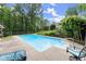 Sparkling in-ground pool with concrete surround, fenced yard, mature trees, and an inviting chair for relaxation at 1713 Dudley Dr, Woodstock, GA 30188