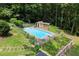 An elevated view of a private in-ground pool, wooden pool house and dive board, surrounded by lush trees and landscaping at 1713 Dudley Dr, Woodstock, GA 30188