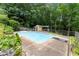 A refreshing in-ground pool surrounded by lush greenery and a wooden pool house provides a private backyard oasis at 1713 Dudley Dr, Woodstock, GA 30188