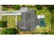 Aerial view of a modern home features a gray roof, an in-ground pool, and a long driveway set in a lush yard at 185 Pebble Trl, Alpharetta, GA 30009