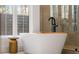 Close up of a soaking tub beside a brass side table and glass shower at 185 Pebble Trl, Alpharetta, GA 30009