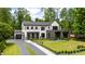 The exterior of this striking two-story home features black trim, white siding and brick, a black garage door, and a manicured lawn at 185 Pebble Trl, Alpharetta, GA 30009