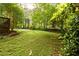 The lush, green backyard features mature trees, a wooden deck, and a patio for outdoor relaxation and entertainment at 4324 Japonica Sw Ct, Lilburn, GA 30047