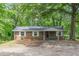 Charming brick home featuring white shutters, covered porch, and mature trees for a picturesque setting at 143 Longview Rd, Fayetteville, GA 30214