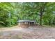 View of home nestled in a wooded area, featuring white trimmed windows and gravel parking area at 143 Longview Rd, Fayetteville, GA 30214