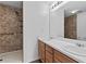 Bathroom featuring double sinks, large mirror, and tiled shower with grab bar at 1608 Indian Way, Cumming, GA 30040