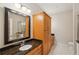 Bathroom featuring dark granite countertops, wood cabinets, and a framed mirror at 3621 Vinings Slope Se # 3510, Atlanta, GA 30339