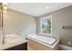 Bright bathroom featuring a soaking tub beneath a window, and a double vanity with recessed lighting at 2055 Cactus Ln, Cumming, GA 30040