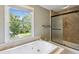 Bright bathroom featuring a soaking tub beneath a window, and a glass-enclosed shower at 2055 Cactus Ln, Cumming, GA 30040