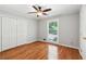 Cozy bedroom features hardwood floors, a ceiling fan, a window, and a double-door closet at 2055 Cactus Ln, Cumming, GA 30040