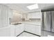 This kitchen features white cabinets, countertops, and tile floor, plus stainless steel refrigerator at 2055 Cactus Ln, Cumming, GA 30040