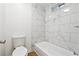Modern bathroom with new toilet and a tub featuring marble-look tile surround at 2745 Saxon Drive, Duluth, GA 30096