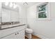 Bathroom with beadboard accent wall, granite vanity, and window with a view of mature trees at 2745 Saxon Drive, Duluth, GA 30096