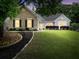 Charming brick home at dusk with well-manicured lawn, landscaping, and curb appeal at 3320 Goldmist Dr, Buford, GA 30519