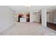 Open-concept living room with neutral carpeting leading to kitchen with cherry-stained cabinets at 3223 Tallon Sw Ln, Atlanta, GA 30311