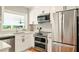 Well-lit kitchen featuring stainless steel appliances, white cabinets, a sink, and a view to the outside at 522 Stell Rd, Woodstock, GA 30188