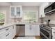 Modern kitchen features stainless steel appliances, white cabinets, and ample counter space by a window at 522 Stell Rd, Woodstock, GA 30188