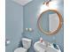 Well-lit half bathroom featuring a classic round mirror and modern fixtures at 1885 Hickory Station Cir, Snellville, GA 30078