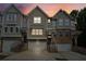 Charming townhomes featuring a brick facade, individual garages, and inviting front entrances at dusk at 4173 Chatham Ridge Dr, Buford, GA 30518