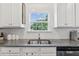Close-up of the kitchen sink and window highlighting the cabinets, granite countertops, and modern tile backsplash at 4173 Chatham Ridge Dr, Buford, GA 30518
