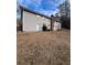 View of the back of a gray home with a brick chimney and a walk-out basement door at 6540 Old White Mill Road Rd, Fairburn, GA 30213