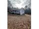 Inviting single-story home showcasing gray siding, black shutters and a gravel driveway surrounded by trees at 6540 Old White Mill Road Rd, Fairburn, GA 30213
