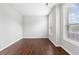 A large, empty bedroom showcasing hardwood floors and two bright windows at 9307 Glenleigh Way, Jonesboro, GA 30236