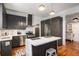 View of the kitchen featuring dark cabinets, stainless steel appliances, a white countertop island, and hardwood floors at 2 N Broad St, Porterdale, GA 30070