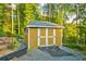 Exterior of the backyard shed with double doors, and a ramp, surrounded by mature trees at 2366 Battle Forest Sw Dr, Marietta, GA 30064