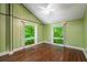 Cozy bedroom with wood-look flooring, vaulted ceiling, and two large windows showcasing the wooded property at 1690 Trotters Ln, Stone Mountain, GA 30087