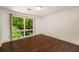 An empty room with dark wood floors and a large window offering a view of dense greenery at 1690 Trotters Ln, Stone Mountain, GA 30087