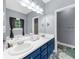 Bathroom with double sinks, a large mirror, blue cabinets, and a window providing ample natural light at 5640 Rolling Oaks Dr, Cumming, GA 30040