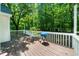 Wooden deck with white railings overlooks a green, lush backyard with a grill, perfect for entertaining at 5640 Rolling Oaks Dr, Cumming, GA 30040
