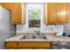 Close up of stainless sink and wood cabinets in a cozy kitchen with natural light at 5640 Rolling Oaks Dr, Cumming, GA 30040