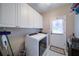 Laundry room featuring updated washer and dryer, overhead cabinets, and access to the backyard at 4645 Waterford Dr, Suwanee, GA 30024