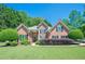 Charming brick home featuring a well-manicured front lawn, mature trees, and classic architectural details at 7045 Grand View Way, Suwanee, GA 30024