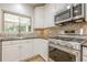 Well lit kitchen featuring stainless steel appliances, mosaic backsplash and a view to the outdoor living area at 7045 Grand View Way, Suwanee, GA 30024