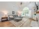 Comfortable living room features vaulted ceilings, hardwood floors, a fireplace, and a large window at 7045 Grand View Way, Suwanee, GA 30024