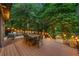 Outdoor living space with dining and lounge areas set on a wooden deck with backyard views and string lights at 570 Martina Ne Dr, Atlanta, GA 30305