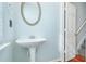 Powder room featuring a pedestal sink, wood floor, and large round mirror at 6887 Slate Stone Se Way # 3, Mableton, GA 30126