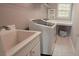 Modern laundry room with front-load washer and dryer, utility sink, and built in folding table at 779 Avonley Creek Trce, Sugar Hill, GA 30518