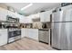 Well-equipped kitchen with stainless steel appliances, granite countertops, white cabinets, and modern laminate flooring at 11072 Pebble Ridge Dr, Hampton, GA 30228