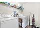 Functional laundry room equipped with a washer, dryer, shelving, and essential cleaning supplies at 11072 Pebble Ridge Dr, Hampton, GA 30228